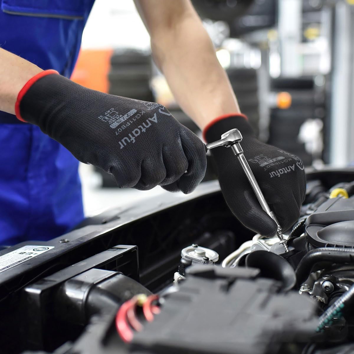 An auto mechanic is repairing a car while wearing a pair of black PU-coated gloves.