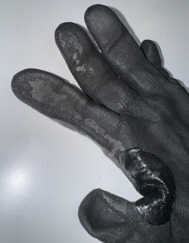A close-up of a peeling nitrile glove coating